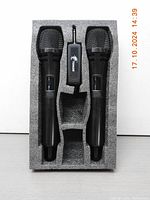 Two black wireless handheld microphones and a wireless receiver in custom foam packaging, showing the entire kit neatly arranged.