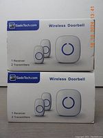 Photo of two unopened boxes each labeled SadoTech Wireless Doorbell with 1 receiver and 2 transmitters per box.