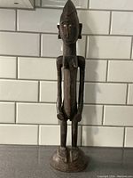 Front view of African carved wooden female figure sculpture showing detailed facial features, arms, torso, and mounted on circular base.