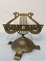 Front angle of the brass music stand showing harp-shaped uprights and ornate base