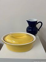 Yellow oval baking dish and blue jug together for size comparison and set display.