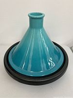 Teal enamel conical lid and black cast iron base of the tagine cookware.