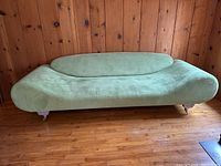 Front view of pale green suede-like sofa against wood-paneled wall