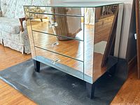 Side-angle view showing mirrored front surfaces and black tapered legs.