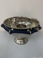 Front three-quarter view of silver plated bowl with wire ring holders and rope accents