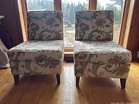 Front view of two armless lounge chairs side by side showing upholstery pattern and wooden legs