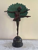 Full front view of bronze dancer sculpture with peacock tail on marble base