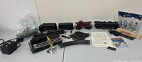 Full overview of train set items including locomotive, freight cars, caboose, curved track pieces, control transformer, and accessory trees on a table.