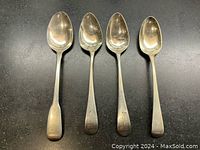 Top view of four polished antique Georgian sterling silver teaspoons laid side by side showing the spoon bowls and handles.