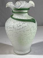 Front view of vase showing round body with pale green and white mottled glass and green curl around neck.