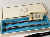 Garland pen and pencil set in original box with instruction leaflets, showing the chrome-like polished finish and design details.
