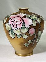 Side view of small round bud vase showing pink hand-painted roses with green leaves on a gold-tone background with raised gold accents.