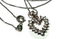 Close-up of sterling silver box chain with spring ring clasp and heart-shaped pendant adorned with clear stones.