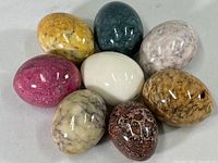 Overview of eight polished stone eggs gathered together showing varying colors and sizes.