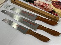 Three Tedron Swords kitchen knives with wood handles laid out with screws for wall mount bracket.