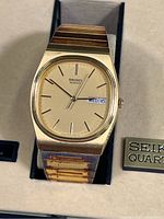 Close-up front image of vintage Seiko gold-tone men’s wristwatch on metal band showing the dial with day-date window and visible tarnishing on band.