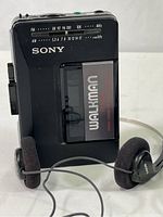 Sony WM-F2015 Walkman cassette player with radio tuner and attached Sony headphones placed on white surface.