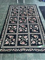 Full view of rectangular rug on tiled floor showing floral block patterns and border.