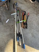 Full assortment of axes, pruning loppers, and telescopic poles laid out on a concrete floor.