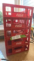 Stack of five red Coca-Cola branded plastic crates shown from a front angle with logo visible.