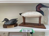 Two duck decoys displayed on a white shelf, showing the full lot.