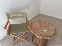 Shows Ducks Unlimited folding director's chair and round wicker table on carpeted floor near wall outlet.