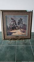 Full view of the framed print showing landscape scene with rocky outcrop, water, and trees.