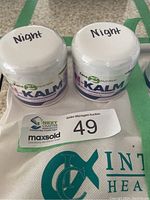 Two sealed jars of N-Kalm night cream with 'Night' written on lids, sitting on a surface with auction tags.