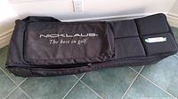 Photo showing the exterior of the black Nicklaus travel golf bag with branded zippered pocket and visible wear.