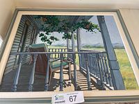 Full view of framed painting showing a porch with two chairs, white railings, green foliage overhead, and a distant landscape.