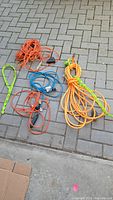 Overview of assortment of five power cords in different colors and lengths laid on pavement