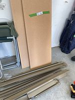 Photo of particleboard wood shelves stacked vertically behind parts on a garage floor.