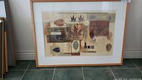 Photo of the framed signed Don Li-Leger print titled Leaf Pattern #2, showing the leaf collage artwork in earth tones with light wood frame and white matting.