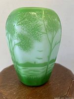 Front angle showing green cameo glass landscape of trees, lake, birds and grass