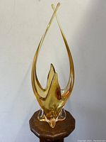 Front and side view of elongated amber abstract glass vase with crossing arms at top.