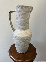 Full view of stippled matte ceramic ewer showing textured grayish glaze and sculptural Bauhaus form with handle and spout.