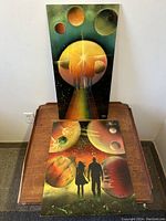 Photo showing the pair of mixed media paintings on board with space-age futuristic themes, titled and signed by Chris Gen.