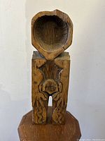 Front view of carved wooden spoon showing the standing man figure and carved scoop bowl.