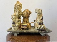 Front view of carved stone mountain village shrine scene on stone platform.