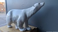 Side view of porcelain polar bear statue showing glossy white finish with gray shading.