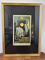 Full photo of framed poster with gold frame and black matting, showing the entire image and context of the piece.