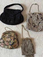 Four antique evening purses arranged on a flat surface showing their overall shapes and designs.