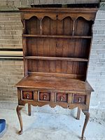 Full view of two-piece wood sideboard showing base and removable hutch against brick background