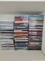 A large stack of assorted music CDs in jewel cases featuring various artists and genres