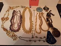 Full view of all costume jewelry necklaces and pendants laid out, showing the variety of materials and styles.
