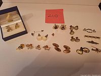 Overview of entire lot on white background: boxed novelty cufflinks, multiple other cufflink pairs, tie bars and pins.