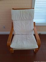 Front angle photo of the wooden frame chair with white padded fabric seat and back cushion, showing the curved armrest design and soft cushion detailing.