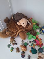 Top view showing large stuffed turtle surrounded by small turtle figurines, keychains, and a colorful globe turtle item.
