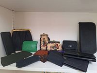 Collection of various antique and vintage purses and wallets arranged on shelf with some textile and leather items, some floral tapestry purses with metal clasps