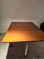 Full table view showing one drop leaf extended and the other side folded down, highlighting the drop leaf functionality and surface finish.